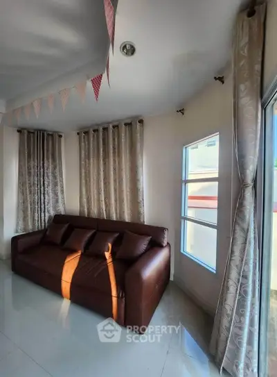 Cozy living room with elegant curtains and a comfortable brown sofa, perfect for relaxation.