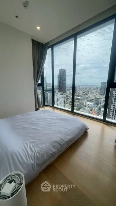 Luxurious bedroom with panoramic city view and floor-to-ceiling windows in modern high-rise apartment.