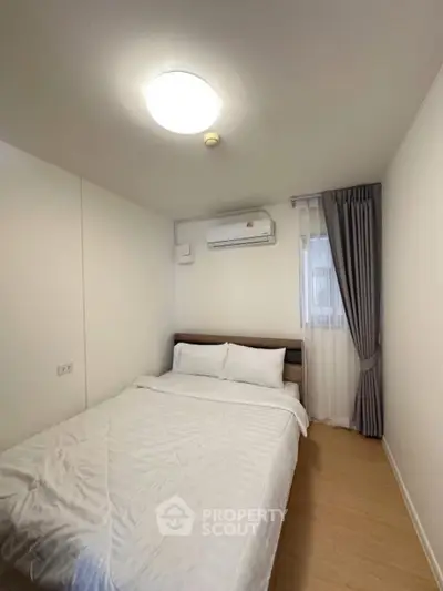 Cozy minimalist bedroom with natural light and air conditioning, perfect for restful nights.