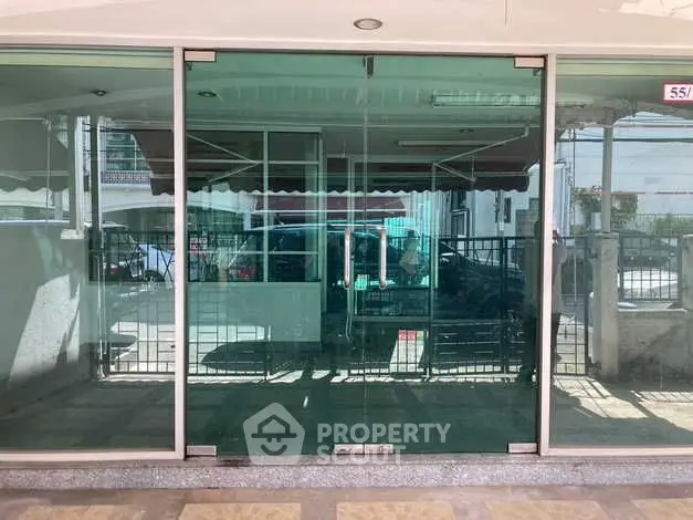 Modern glass entrance with reflective surface and urban surroundings.