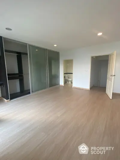 Spacious bedroom with wooden flooring and built-in sliding door closet