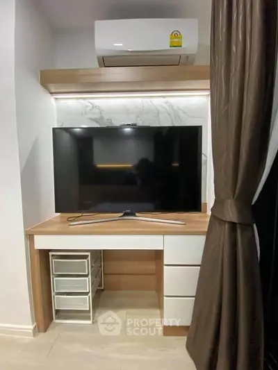 Modern living room corner with TV and air conditioning, featuring sleek furniture and elegant curtains.