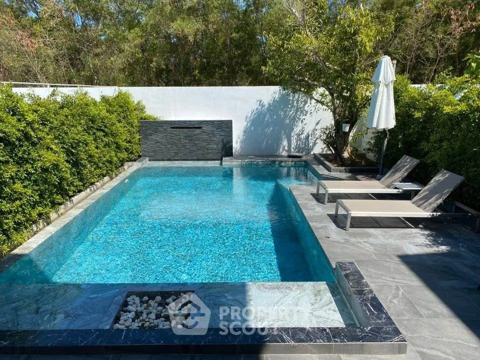 Luxurious private pool with sun loungers and lush greenery, perfect for relaxation and leisure.