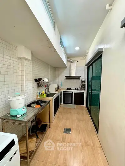 Modern kitchen with sleek design, featuring white subway tiles and wooden flooring.