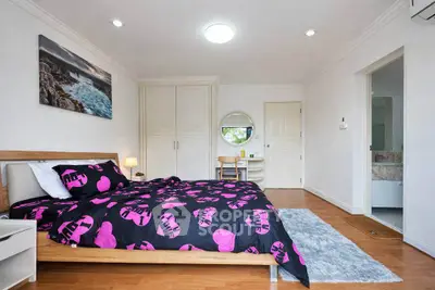 Spacious bedroom with modern decor and ensuite bathroom, featuring stylish bedding and ample natural light.