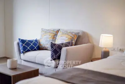 Cozy living room with stylish sofa and decorative pillows, perfect for relaxation.