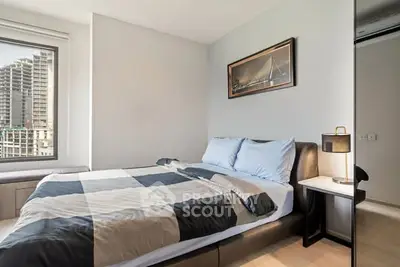 Modern bedroom with large window and stylish decor in urban apartment.
