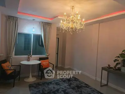 Elegant living room with chandelier and modern decor, featuring cozy seating and ambient lighting.