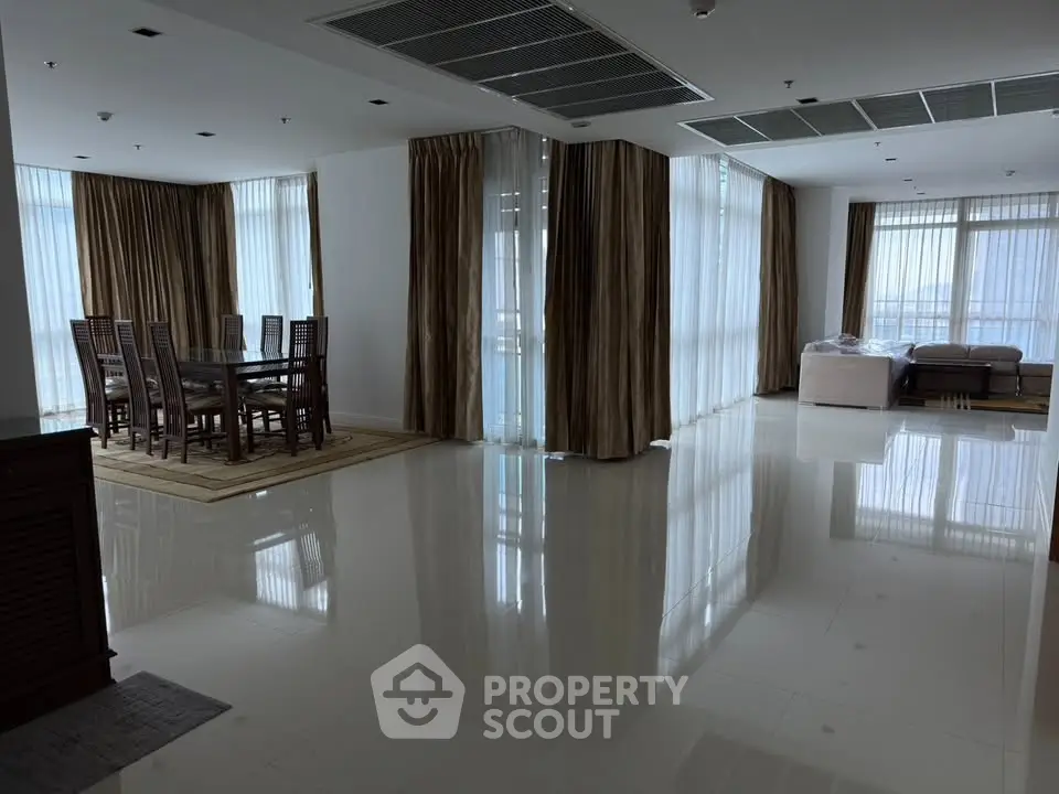 Spacious modern living room with dining area and large windows offering natural light.