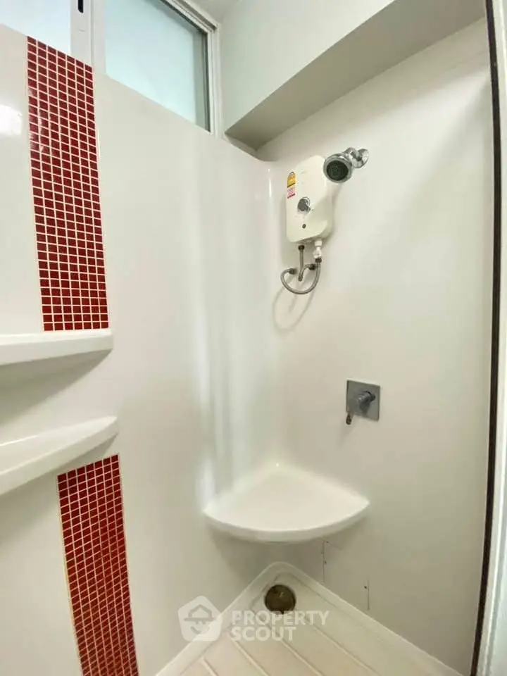 Compact bathroom with modern shower and red tile accents