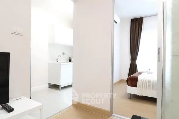 Modern apartment interior with bedroom and kitchen view, featuring sleek design and natural light.