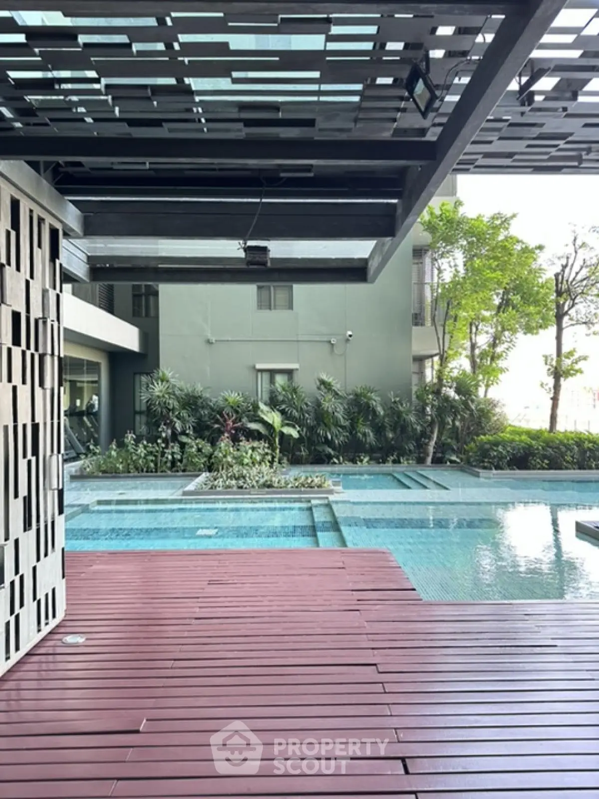 Modern apartment pool area with stylish deck and lush greenery