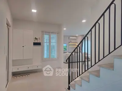 Modern interior with staircase and cozy living area, featuring sleek design and ample natural light.