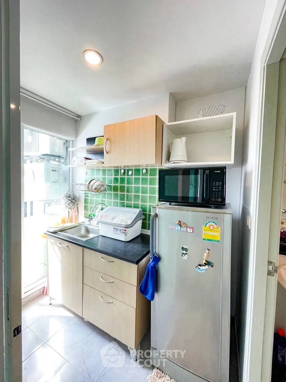 Compact kitchen with green tile backsplash and modern appliances