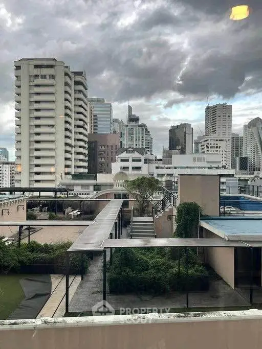 Stunning cityscape view from a rooftop terrace with lush greenery and modern architecture.