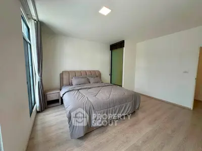 Spacious bedroom with modern decor and large window for natural light
