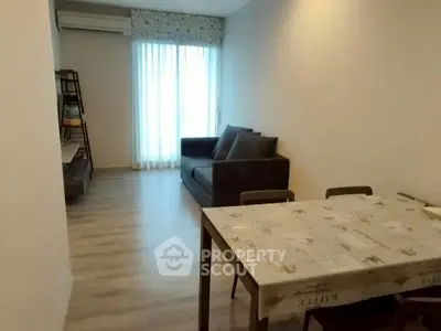 Cozy living room with modern decor and natural light, featuring a comfortable sofa and dining area.