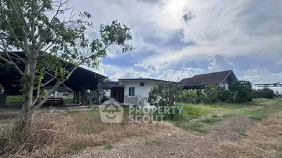 Charming rural property with spacious land and traditional architecture under a bright sky.