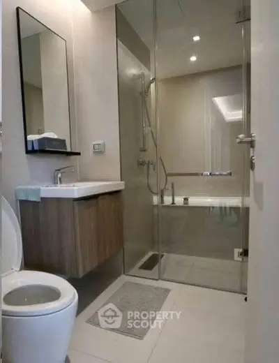 Modern bathroom with glass shower and sleek vanity in contemporary apartment.