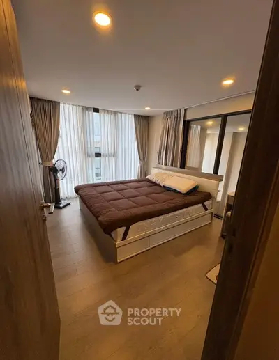 Spacious bedroom with large windows and modern decor in a luxury apartment.