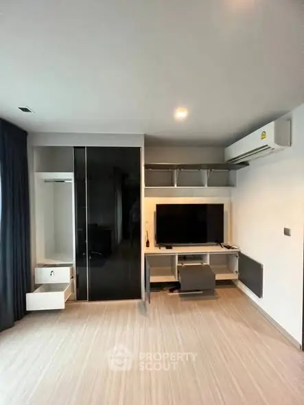 Modern living room with sleek TV setup and air conditioning in a stylish apartment.