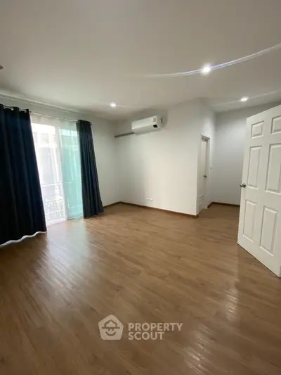 Spacious living room with elegant hardwood flooring, modern lighting, and large windows draped in luxurious dark curtains, offering a blank canvas for personalized decor.