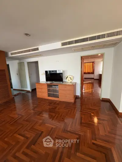 Spacious living room with elegant wooden flooring and modern entertainment center.