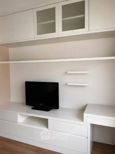 Modern minimalist living room with sleek white cabinetry and TV setup.