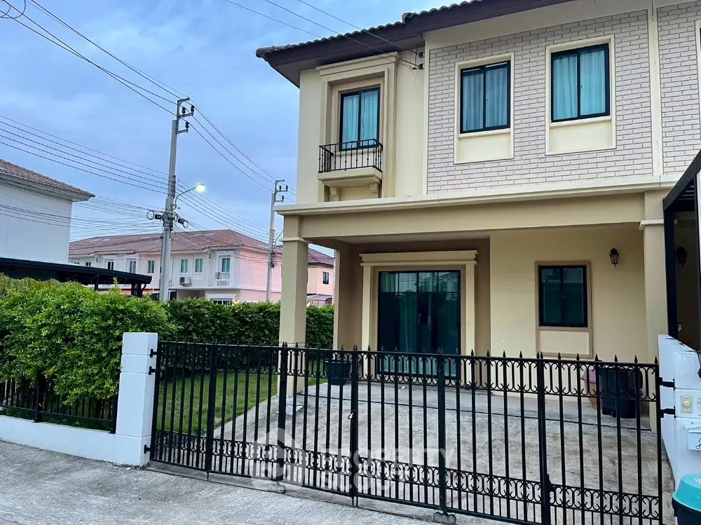 Charming two-story house with gated driveway and lush greenery in a serene neighborhood.