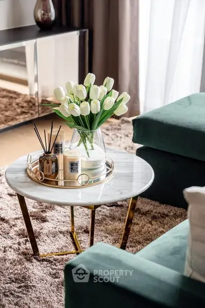 Elegant living room with stylish decor and plush green sofa, featuring a chic marble coffee table with tulip centerpiece.