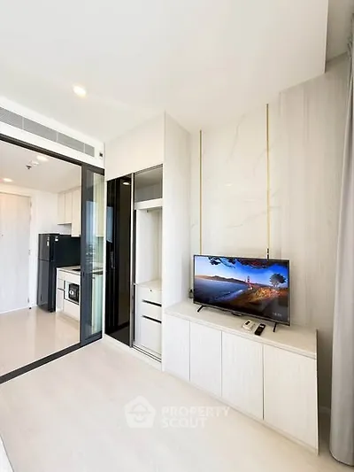 Modern living room with sleek design and integrated kitchen appliances in a bright apartment.