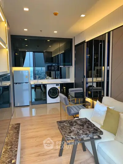 Modern living room with open kitchen, featuring sleek appliances and stylish decor.