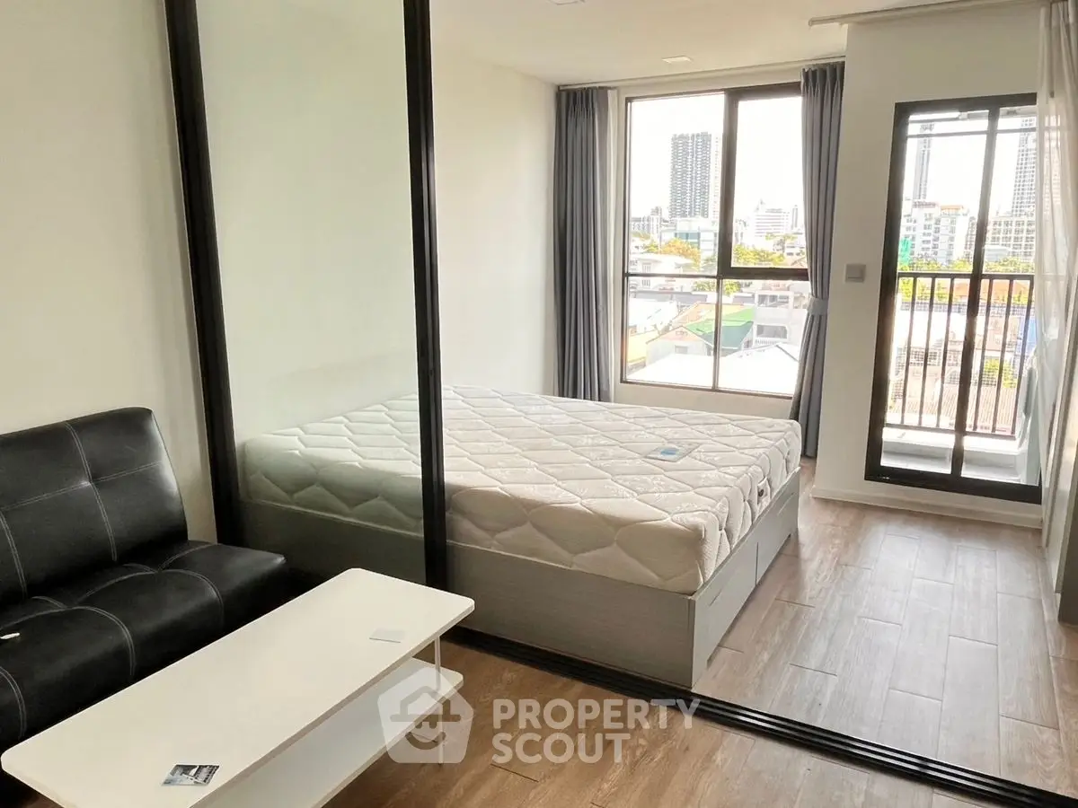 Modern bedroom with glass partition and city view balcony in urban apartment