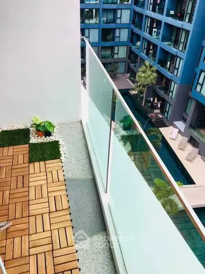 Modern apartment balcony with glass railing and pool view