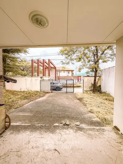 Spacious driveway leading to a secure gated entrance with a view of a suburban neighborhood.