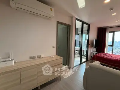 Modern apartment interior with bedroom, living area, and city view, featuring sleek furniture and air conditioning.
