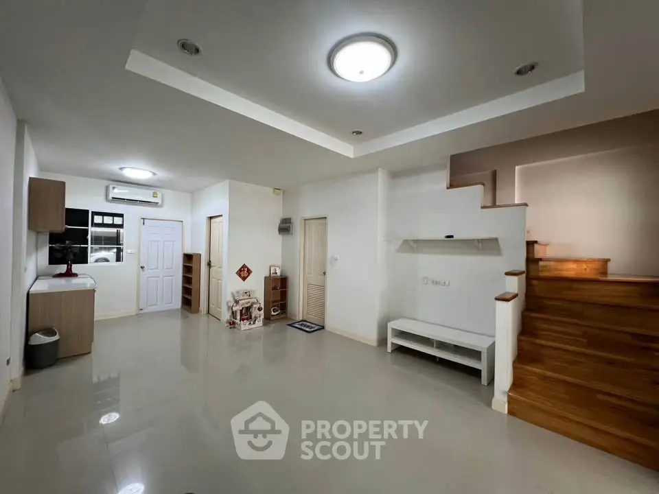 Spacious modern living room with wooden staircase and sleek lighting