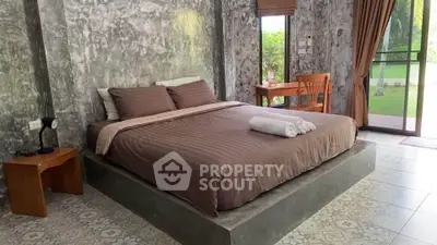 Modern bedroom with stylish concrete walls and large window overlooking garden