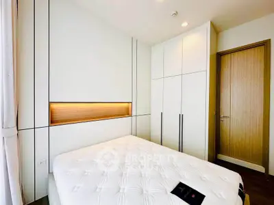 Modern bedroom with sleek white wardrobe and cozy bed in a bright apartment.