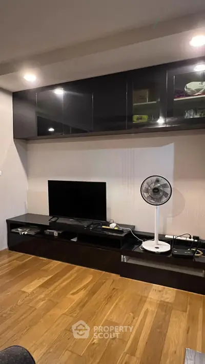 Modern living room with sleek black entertainment unit and wooden flooring