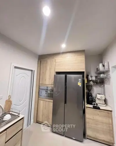 Modern kitchen with sleek appliances and wooden cabinetry, featuring a built-in oven and spacious fridge.