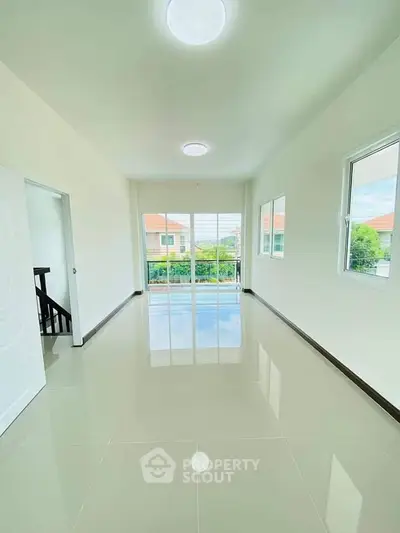 Bright and spacious room with glossy tiled floors and large windows offering a serene view.