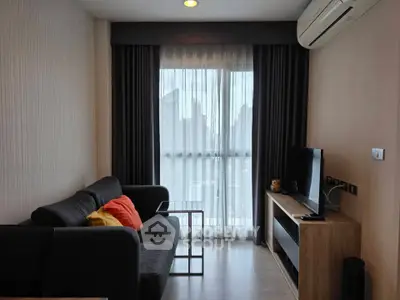Modern living room with city view, featuring sleek furniture and large window for natural light.