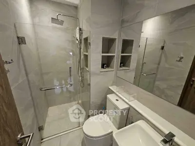 Modern bathroom with glass shower and sleek fixtures in a contemporary apartment.