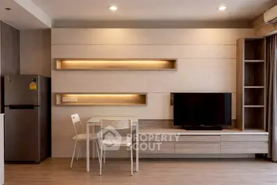 Modern living room with sleek TV unit and dining area in stylish apartment.
