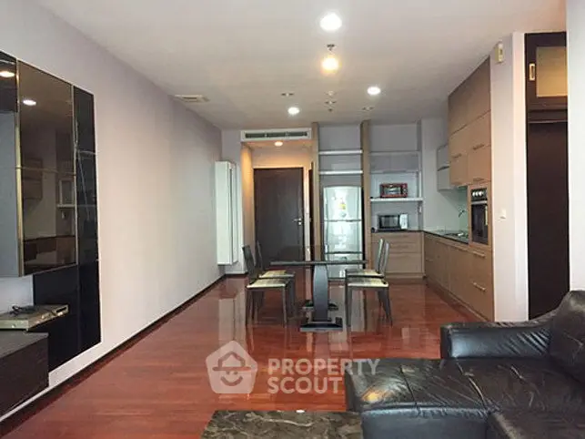Spacious modern living room with open kitchen and sleek wooden flooring.