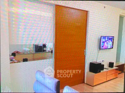 Modern living room with sleek wooden door and wall-mounted TV