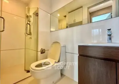 Modern bathroom with glass shower and sleek vanity in contemporary home.