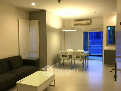 Modern living room with sleek furniture and open layout, featuring a cozy dining area and large windows.
