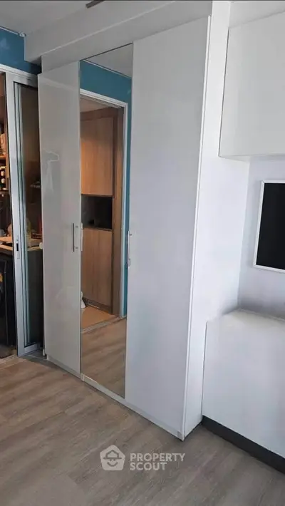 Modern apartment interior with sleek white wardrobe and wooden flooring